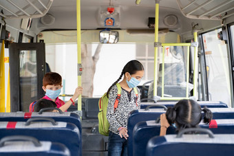 孩子们医疗面具未来内部学校公共汽车坐着座位维护社会距离由于冠状病毒科维德流感大流行概念学校重开回来学校
