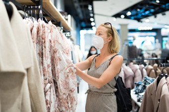 时尚女人穿保护脸面具购物衣服重开零售购物商店正常的生活方式电晕病毒流感大流行