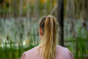 年轻的高加索人女人站回来相机晚上沼泽模糊干树cattai背景