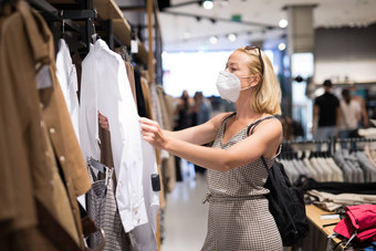 时尚女人穿保护脸面具购物衣服重开零售购物商店正常的生活方式电晕病毒流感大流行