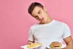 男人。汉堡薯条快食物卡路里粉红色的背景新鲜的食物情感模型