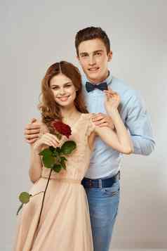 年轻的夫妇浪漫拥抱的关系约会红色的玫瑰光工作室背景
