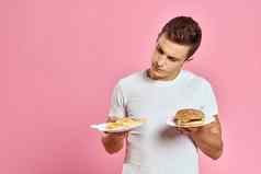 男人。汉堡薯条快食物卡路里粉红色的背景新鲜的食物情感模型