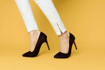 女腿黑色的鞋子时尚有吸引力的白色牛仔裤黄色的<strong>背景</strong>