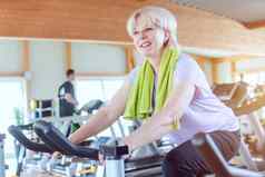 高级女人锻炼健身自行车健身房
