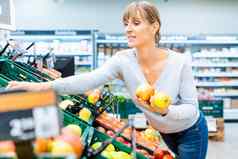 女人测试新鲜的水果超市架子上