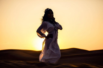 美丽的女人站沙漠日落