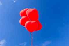 红色的心形状的氦气球飞行天空