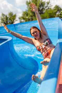 快乐年轻的丰满高加索人女人游乐设施提高了手水幻灯片水公园
