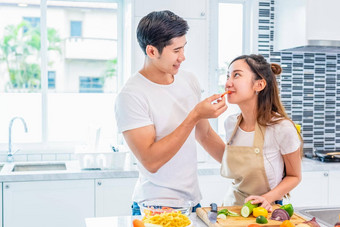 亚洲的男朋友喂养水果蔬菜女朋友准备晚餐首页厨房夫妇家庭概念度蜜月假期男人。女人烹饪幸福的