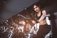 亚洲健身女人自行车旋转健身房美丽的年轻的女工作健身房自行车医疗健康的概念锻炼有氧运动主题
