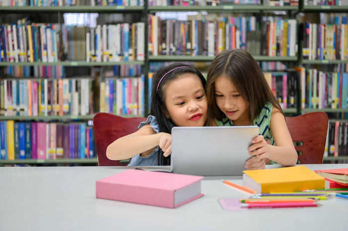 快乐可爱的女孩玩平板电脑计算设备图书馆学