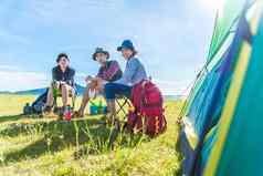 集团旅行者野营野餐草地帐篷前景山湖背景人生活方式概念在户外活动休闲主题背包客徒步旅行者主题
