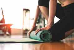关闭运动女人折叠瑜伽床垫体育运动健身健身房培训中心背景锻炼席滚动保持瑜伽类锻炼体育运动培训概念手地毯