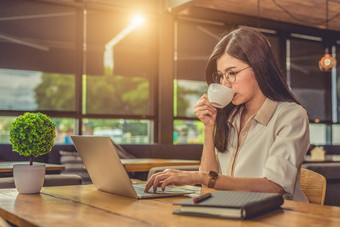亚洲工作女人移动PC喝咖啡咖啡馆人生活方式概念技术业务主题自由占领主题工作狂在一夜之间概念