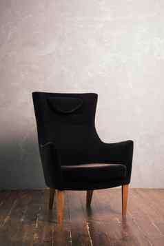 豪华的黑色的薇洛尔扶手椅站织构墙黑暗木地板上