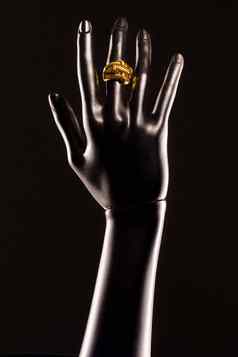 黑色的塑料手人体模型黑色的背景黄金环手指