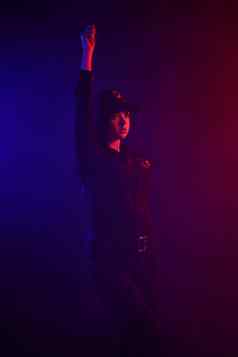 红发的女警察官摆姿势相机黑色的背景红色的蓝色的背光