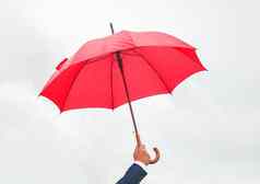男人的手持有红色的开放伞光天空
