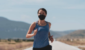 确定健身女人短衣服穿红色的保护脸面具运行在户外城市冠状病毒爆发科维德物理慢跑活动体育<strong>运动健身</strong>