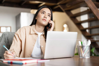 业务女人亚洲女孩工作首页写作客户端笔记会说话的移动电话坐着移动PC