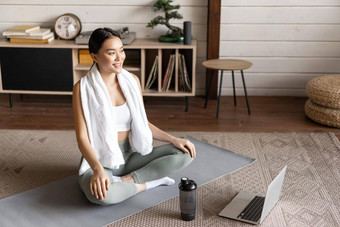 体育运动生活方式概念微笑年轻的亚洲女人瑜伽首页<strong>遵</strong>循冥想移动PC坐着Zen构成地板上席