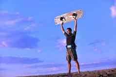 肖像年轻的风筝冲浪男人。海滩日落