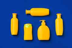 明亮的黄色的瓶防晒霜产品黑暗蓝色的纸背景