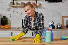 年轻的女人家庭主妇橡胶手套擦拭表格超细纤维布首页厨房