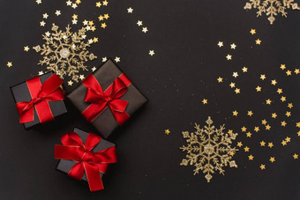 黑色的礼物盒子红色的丝带黄金五彩纸屑背景优雅的圣诞节背景现代金圣诞节装饰球礼物盒子五彩纸屑星星黑暗黑色的背景平设计前视图复制空间