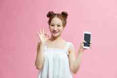 有吸引力的年轻的女孩显示手势持有空白屏幕移动电话孤立的粉红色的背景