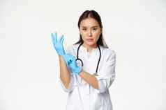 自信女护士医生把橡胶医疗手套病人临床检查站医疗保健工人统一的白色背景