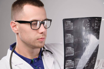 年轻的高加索人医生放射科医生x射线医生白色外套眼镜听诊器持有x射线手