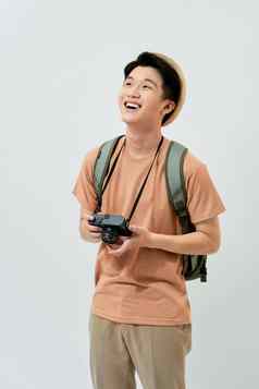 肖像快乐的年轻的亚洲旅游男人。持有数字相机采取照片站白色背景