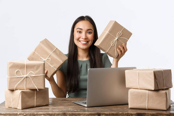 小业务主人启动电子商务概念微笑亚洲女人很多订单坐着表格移动PC包装客户端购买货物盒子航运白色背景