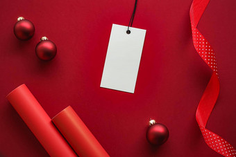圣诞节出售假期时尚设计概念空白服装标签圣诞节装饰饰品红色的纸背景平铺模型