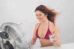 红发微笑女人比基尼饮料冷喝享受吹风电风扇白色背景气候控制热夏天一天