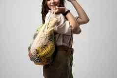 女孩持有网购物袋蔬菜绿色塑料袋浪费塑料免费的生态友好的概念可持续发展的生活方式