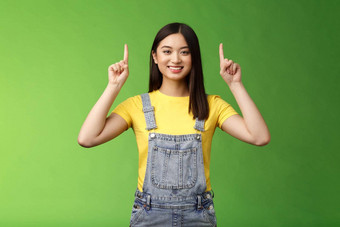 友好的可爱的好看的亚洲浅黑肤色的女人女指出提高手指前广告自信的显示促销微笑满意<strong>介绍产品</strong>绿色背景