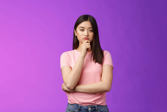 审判的严肃的表情聪明的亚洲女孩给专家触摸下巴深思熟虑的眯着眼看可疑的不确定的使决定选择产品思考思考计划紫色的背景
