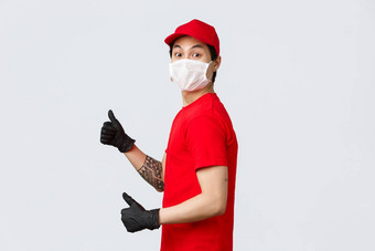 哇快交付兴奋亚洲交付的家伙红色的帽t恤穿保护医疗面具手套转相机竖起大拇指推荐快递服务在线购物概念