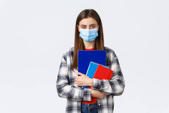 冠状病毒流感大流行科维德教育回来学校概念年轻的女学生医疗面具持有笔记本电脑类大一新生大学个人保护口罩
