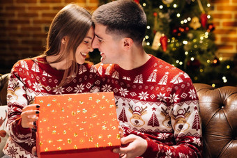 肖像浪漫的夫妇开放现在礼物盒子晚上装饰圣诞节树概念假期浪漫惊喜快乐男人。使圣诞节礼物亲爱的女人