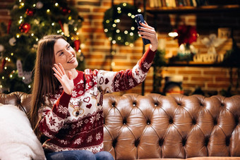 年轻的高加索人女人聪明的电话视频调用会说话的朋友的男朋友圣诞节树装饰点缀生活房间首页圣诞节一年假期节日