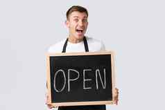 小零售业务主人咖啡馆餐厅员工概念热情的英俊的服务员通知客户大开放显示开放标志微笑惊讶白色背景