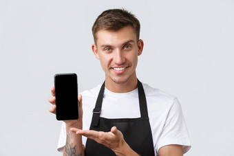 咖啡馆餐厅咖啡商店主人零售概念英俊的友好的微笑服务员推销员显示移动电话屏幕演示应用程序智能手机