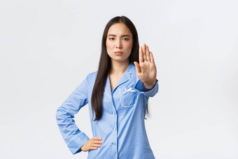 严肃的表情确定亚洲女孩蓝色的睡衣扩展手显示停止禁止行动使警告不赞成坏行为禁止白色背景