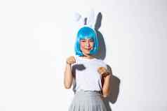 肖像美丽的愚蠢的日本女孩蓝色的假发兔子耳朵扮万圣节聚会，派对微笑卖弄风情的站白色背景