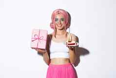 美丽的女孩庆祝生日粉红色的假发持有礼物生日蛋糕站白色背景