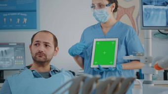 口腔学护士垂直持有平板电脑绿色屏幕